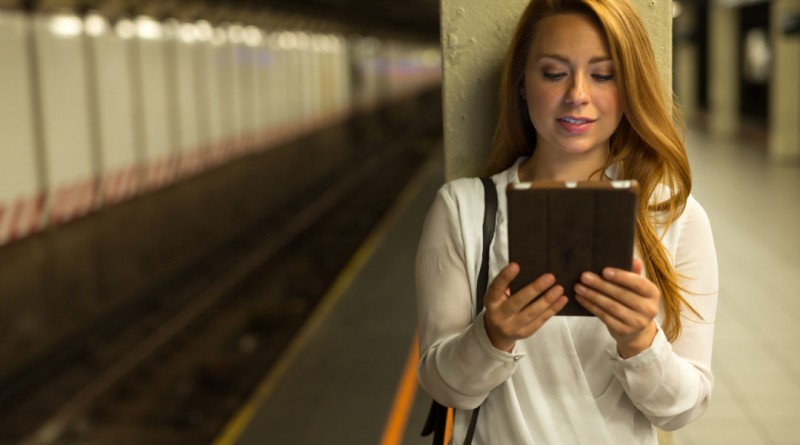 Young caucasian woman in city using tablet pc computer at subway platform