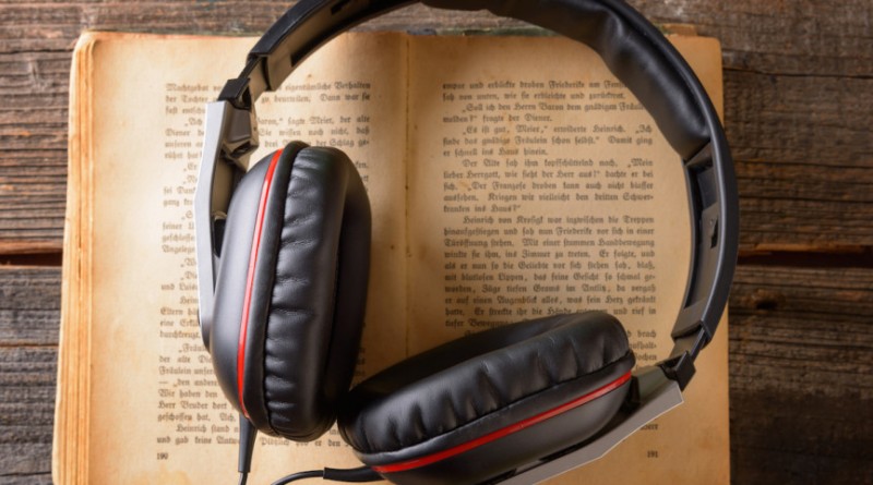 Headphones on the old book. Concept of listening to audiobooks.